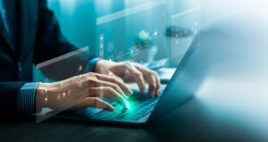 A man in a suit types on a laptop keyboard with AI graphics overlaid above his hands.