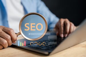 A man holds a magnifying glass over an SEO graphic above a silver laptop.