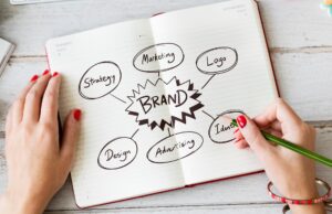 A woman drawing in a notebook with the word brand and several describing words around it.