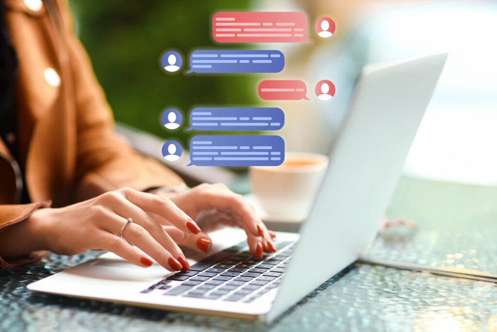 A person types on a silver laptop with a graphic overlay of live chat floating above their hands.