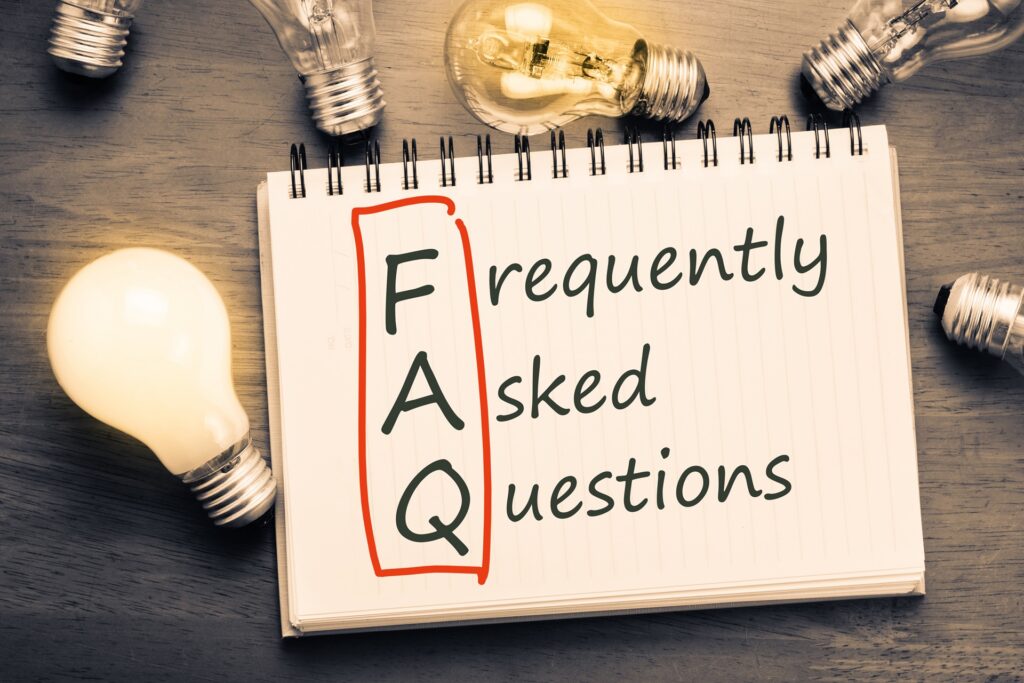 The words frequently asked questions written on paper next to light bulbs resting on a table.