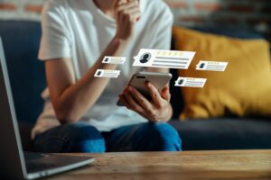 A woman sitting on a couch looking at client reviews with various star ratings on her phone.