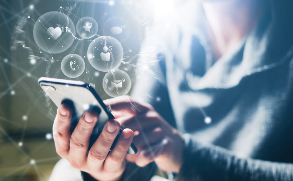 A woman on her phone interacting with it while social media icons float above it.
