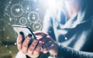 A woman on her phone interacting with it while social media icons float above it.