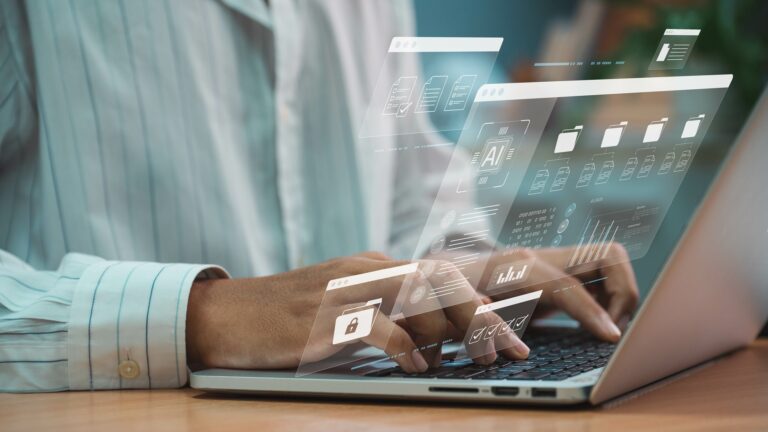 A person typing on a silver laptop with AI graphics overlaid.